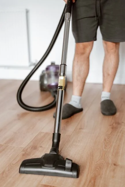 An adult male cleaning a glass window indoors, with attention on domestic tasks and maintaining cleanliness.